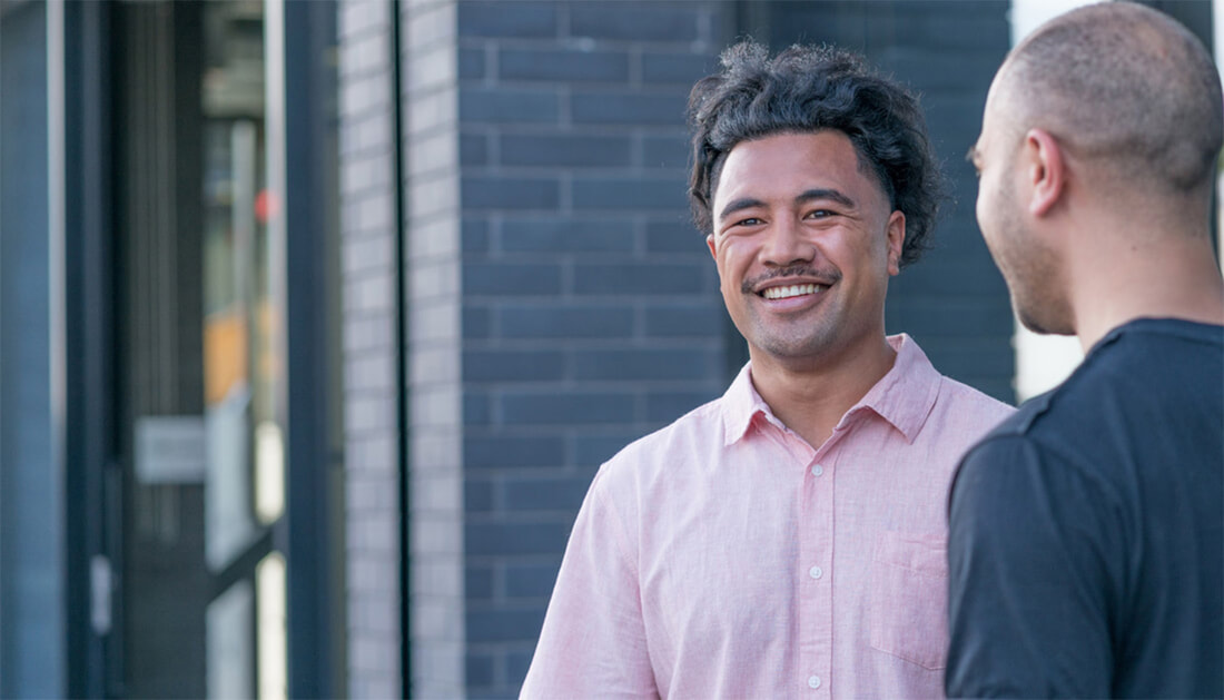 Two men standing outside an office smiling and chatting.